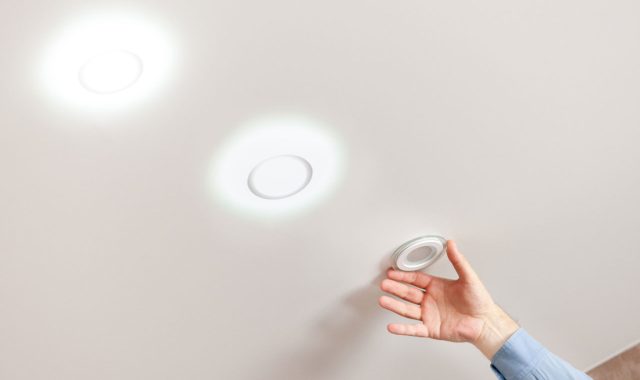 A person installing an IC-rated recessed light fixture into a ceiling, ensuring safe and efficient lighting.