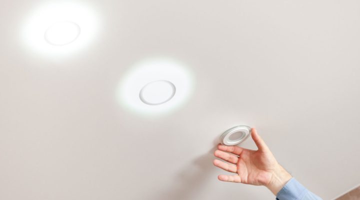 A person installing an IC-rated recessed light fixture into a ceiling, ensuring safe and efficient lighting.