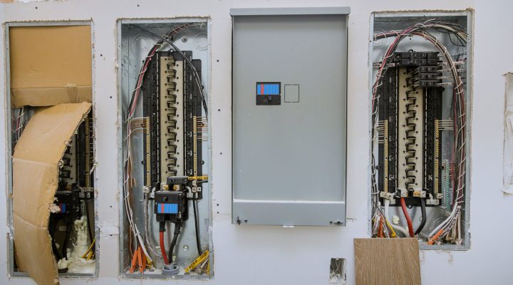 An open electrical panel with multiple circuit breakers and neatly organized wiring, set within a wall.
