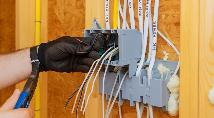 A skilled electrician organizes multiple labeled wires into a junction box, ensuring proper installation.